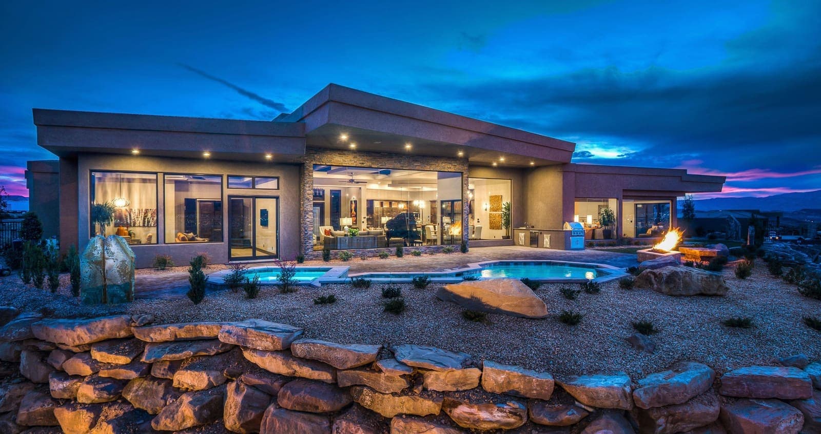 Vivienda unifamiliar con piscina y jardín iluminados al anochecer.